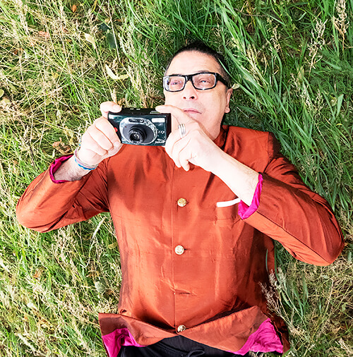 A person lying in grass holding a camera AI-generated content may be incorrect.